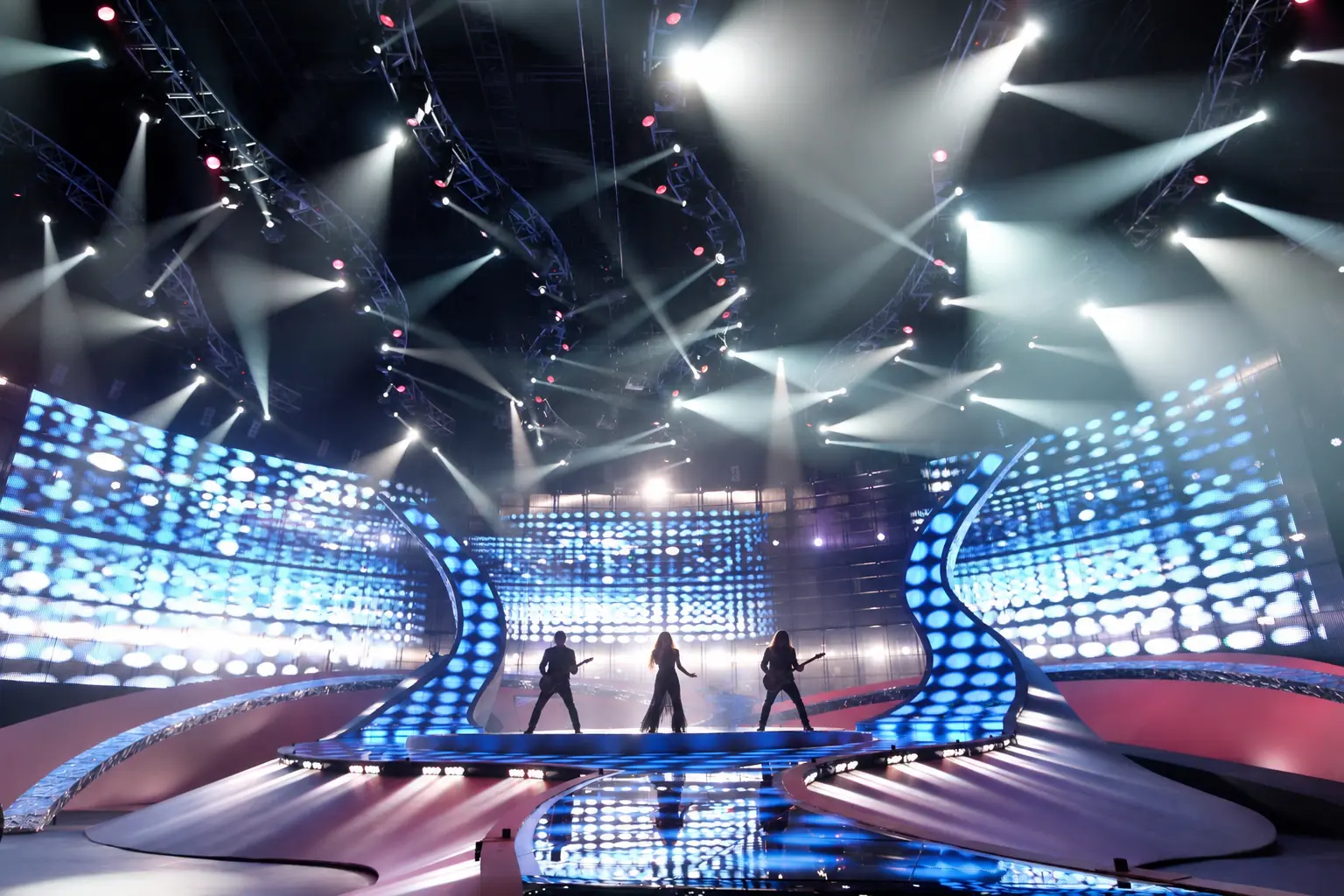 Broadcast stage with performers among sweeping blue light